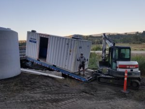 A man on a truck unloading a container.