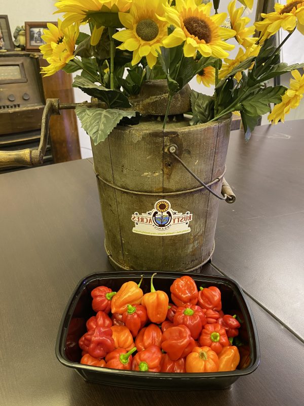 A bucket of flowers and some tomatoes on the table