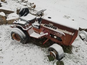 A red and white tractor is in the snow.