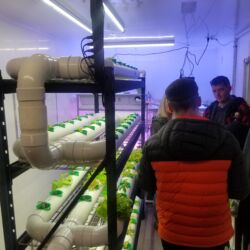 A group of people standing around in front of an indoor farm.